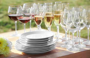 Plates and glasses with wine and champagne on wooden table, close up view