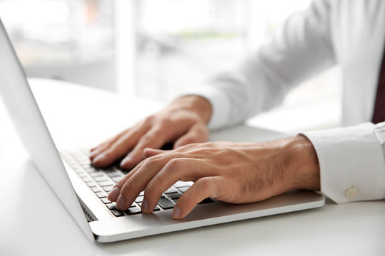 Male hands typing on laptop at office