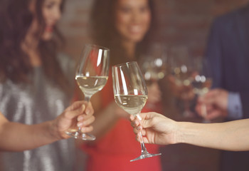 Female hands toasting with glasses of white wine, closeup
