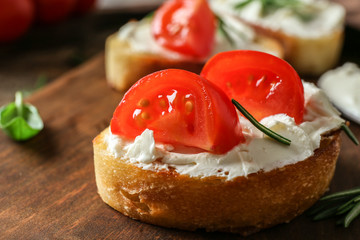 Delicious bruschetta with tomatoes on wooden board, closeup