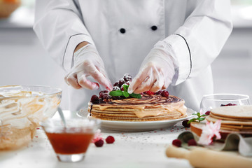 Cooking concept. Professional confectioner decorating tasty cake with mint