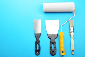 Painting roller, brush and spatulas on blue background