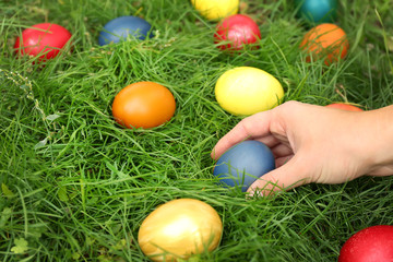 Woman hand holding Easter egg on green grass background