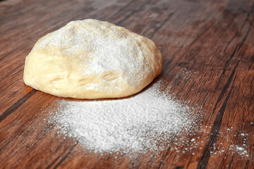 Fototapeta na wymiar Raw dough and flour on wooden kitchen table