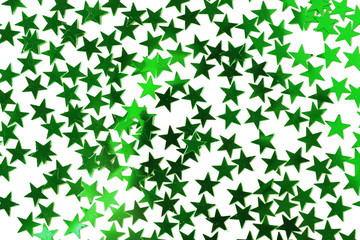 Bright confetti in shape of stars, on green background. Close up