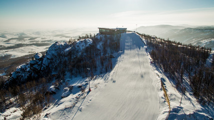 Skiers and snowboarders slide down mountainside near lake Bannoe. Aerial