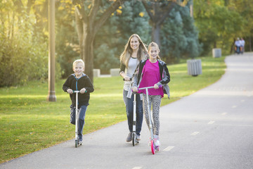 A women and her children riding together outdoors on a paved bike pathway. Smiling and having fun...