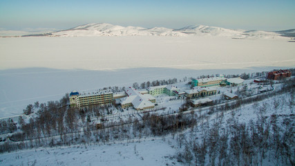 Resort on frozen lake in the mountains. Aerial. Ural, Russia