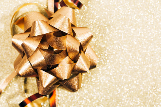 Golden ribbon bow with little sparkles in bokeh