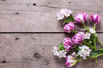 Fototapeta na wymiar Tulips and apple tree flowers on aged wooden background.