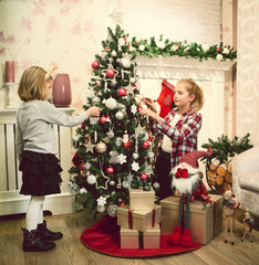 Little girls decorating Christmas tree and preparing gifts