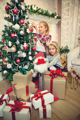 Little girls decorating Christmas tree and preparing gifts