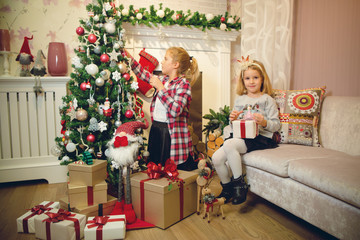 Obraz na płótnie Canvas Little girls decorating Christmas tree and preparing gifts