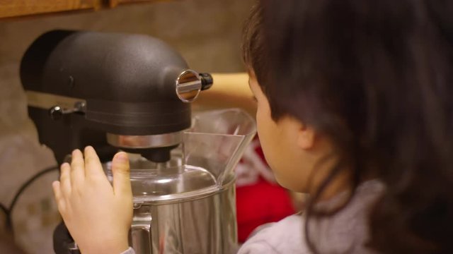 Siblings using an electric mixer at home