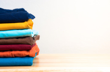 Stack of colorful clothes on wood table, Housework and objects concept, Gradient blurred background