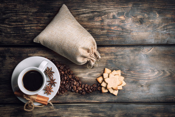 Coffee composition with black coffee, cinnamon and cookies on the old wooden