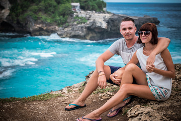 Fototapeta premium Attractive young happy romantic couple on the tropical island Nusa Lembongan, Indonesia. Happy honeymoon during their vacation in Asia. Romantic scene on the cliff. Ocean on a background.