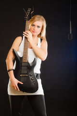 Obraz premium Blonde woman holding electric guitar, black background