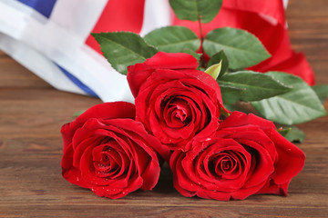 Red roses with American flag on wooden background, closeup