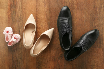 Family concept. Shoes for parents and child on wooden background