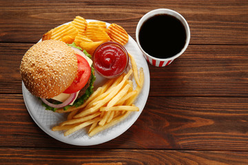 Tasty burger with snacks and coke on wooden table
