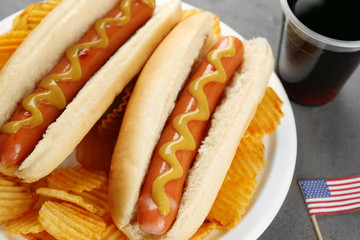 Hot dogs with mustard and chips on plate, closeup