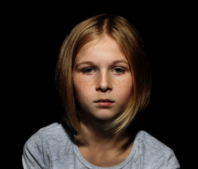 Portrait of sad little girl on black background