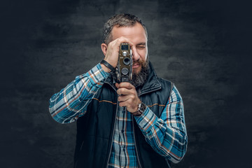Bearded middle age male holds vintage 8 mm video camera.