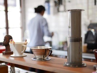 Coffee cup in couture with blurred barista background.