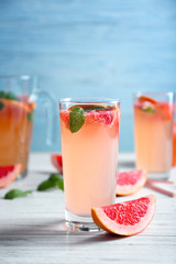 Glass of refreshing grapefruit drink on table