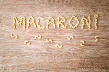 Macaroni inscription made from macaroni on the wooden table. Healthy eating and lifestyle.