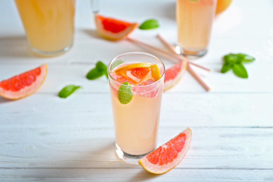 Glass of refreshing grapefruit drink on table