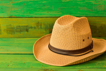 Brown cowboy hat on green wooden texture background