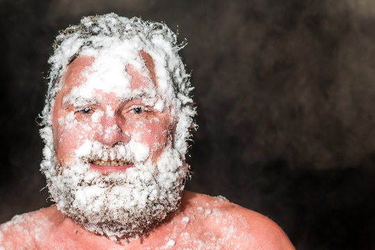 Adult bearded man covered with snow in the sauna