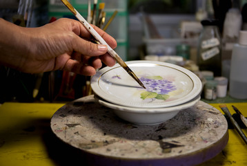 Asian woman hand painting ceramic plate