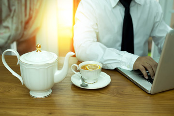 Fototapeta na wymiar Businessman hands using notebook with cup of tea and lemon on wo