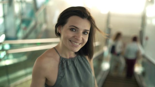 Young woman using smartphone riding on the escalator stairs
