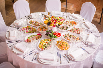 Round table with Italian food, white tablecloth candelabrum