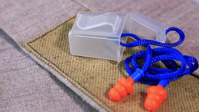 Protective working burlap gloves and earplugs on rotating surface. Personal protective equipment background. Industrial safety concept.