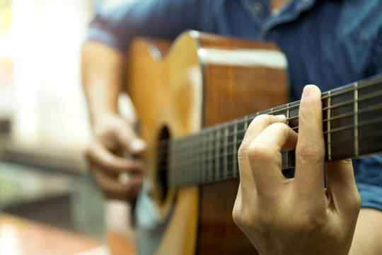Selected focus man playing acoustic guitar  indoors