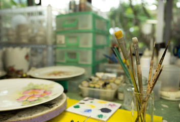 Paint brushes in a jar with paint tool in the background