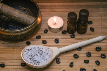 Spa concept.Coffee scrub, coffee beans, singing bowl, aroma oil, candle on straw mat  background