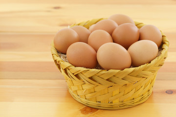 Chicken eggs in a wicker straw on wooden background