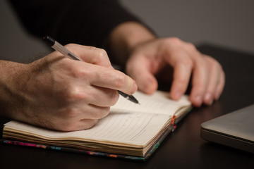 male hand writing in a notebook