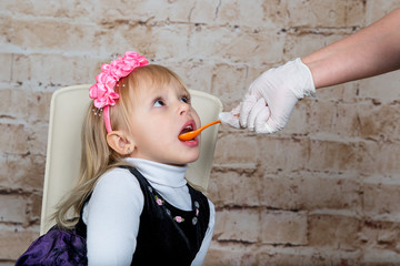 Doctor hand giving spoon dose of medicine liquid drinking syrup to child