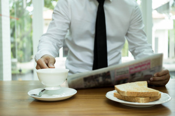 Businessman hand holding coffee cup  and reading newspaper with