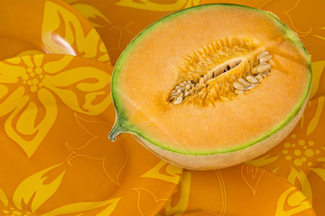 One half of a melon on the orange plate