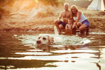 The mother,father,son and dog sitting  in the lake