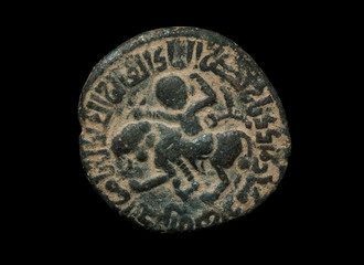 Ancient bronze islamic coin with image of person riding the lion isolated on black