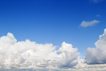 Blue sky with fluffy white clouds background.